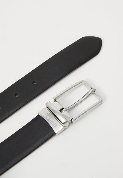 Juodas odinis diržas su stačiakampiu sidabro spalvos metaliniu sagtimi. Sagtis turi lygią apdailą ir išgraviruotą prekės ženklą. Diržas turi kelias skylutes reguliavimui.