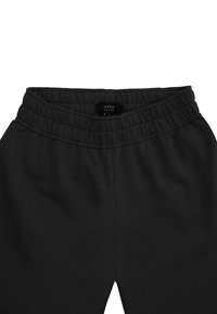 Czarne dresy wykonane z miękkiej tkaniny; posiadają elastyczny pas z marszczoną fakturą oraz metkę z napisem "OPRA", rozmiar M-L.