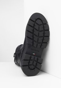 Semelle de bottes en cuir noir avec un motif de semelle profond, dotée d'une fermeture éclair latérale et d'un logo en relief. Fabriqué en Italie.