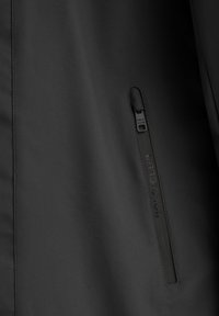 Giacca nera con una texture liscia, tasca con zip angolata e logo impresso "POLO CLUB" vicino alla zip. Design minimalista.