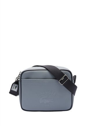 Graue rechteckige Umhängetasche aus strukturiertem Material. Sie verfügt über ein vorderseitiges, geprägtes Logo und einen verstellbaren dunklen Riemen mit einer silbernen Schnalle.