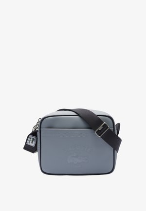 Graue rechteckige Umhängetasche aus strukturiertem Material. Sie verfügt über ein vorderseitiges, geprägtes Logo und einen verstellbaren dunklen Riemen mit einer silbernen Schnalle.