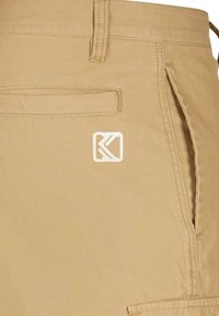 Khaki nohavice s hladkým povrchom, s prednou kapsou a vyšitým logom v dolnom rohu. Jednoduché šitie a strihový dizajn.