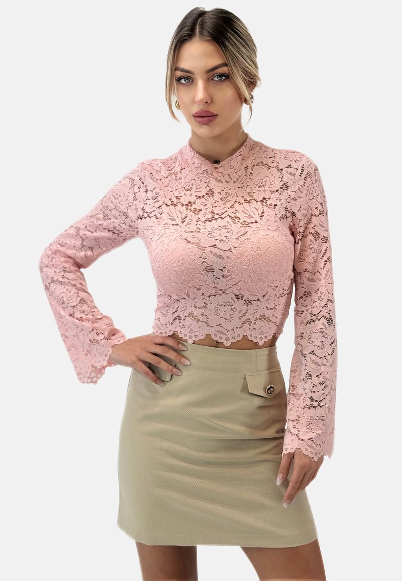 Pinker Spitzen-Crop-Top mit langen Ärmeln, floralem Muster und gewelltem Saum, kombiniert mit einem beigen Minirock mit seitlicher Tasche und Knopfdetail.