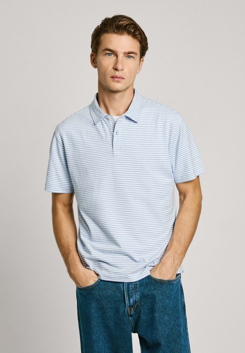 Světle modrá polo košile s krátkým rukávem, tenké bílé pruhy, límečkový design, volný střih; kombinováno s modrými džíny.