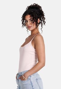 Ljusrosa åtsittande bodysuit med tunna band, som har en rundad halsringning och mjuk textur. Matchad med högmidjade ljusblå jeans.