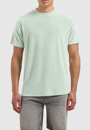 Minzgrünes Kurzarm-T-Shirt aus weichem Stoff mit lockerer Passform, mit einem kleinen weißen Logo auf der linken Brust und einem gerundeten Ausschnitt.