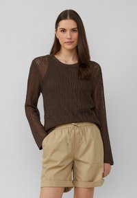 Pull en tricot brun à manches longues avec un motif texturé, associé à un short beige clair avec cordon de serrage, revers aux poignets et poches latérales.