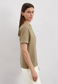 Khaki poloshirt met korte mouwen, vijfknopssluiting en een rechte zoom. Gemaakt van gladde stof met subtiele stikdetails.