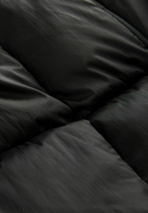 Černá prošívaná tkanina s lesklou, hladkou strukturou. Design obsahuje prošívané panely vytvářející nadýchaný vzhled, který zdůrazňuje minimalistický styl.