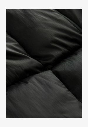 Tela de tejido acolchado negro con una textura brillante y suave. El diseño presenta paneles cosidos que crean una apariencia esponjosa, destacando un estilo minimalista.