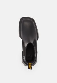 Svart chelsea-boot med slät läderöverkänsla, elastiska sidopaneler och texturerad dragflik. Tjock sula med rund tå och minimal sömnad.