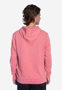 Roze hoodie van katoen, met een capuchon, lange mouwen en een relaxte pasvorm. De achterkant heeft een gladde textuur zonder patronen.