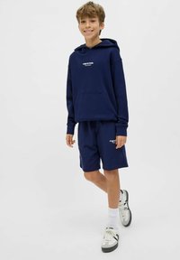 Set di felpa con cappuccio e pantaloni corti blu navy, realizzato in tessuto morbido. Presenta una tasca frontale, polsini a coste e dettagli del logo bianco sul petto e sui pantaloni corti.