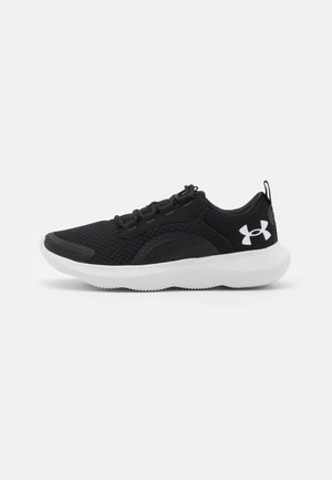 Chaussure de sport noire avec une tige en tissu maillé, semelle en caoutchouc blanche et accents noirs. Elle présente des lacets plats et un design de bout arrondi.