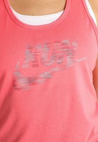 Pink athletic tank top with a rounded neckline featuring a silver Nike logo and “RUN” text. Made from breathable, lightweight fabric.