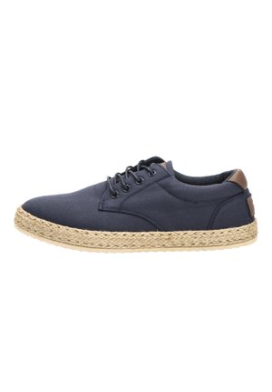Zapato casual azul marino con cordones, suela de cuerda trenzada y acento de cuero marrón en el talón, mostrado desde el lado exterior sobre fondo blanco.