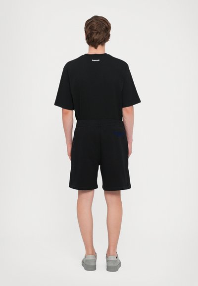 Ensemble composé d'un t-shirt noir à manches courtes et d'un short, avec un design simple, en matériau coton, offrant un ajustement confortable, et avec un logo discret à l'arrière.