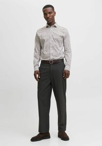 Camicia con bottoni dal motivo floreale in colori chiari, abbinata a pantaloni eleganti scuri e mocassini marroni. Una cintura a tinta unita accentua l'outfit.