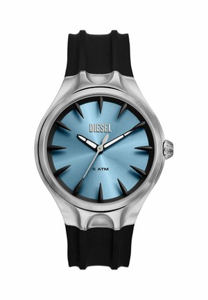Montre-bracelet ronde Diesel avec cadran bleu, boîtier argenté, index heures en forme de pointes noires, aiguilles lumineuses et bracelet en silicone noir, étanche 5 ATM.