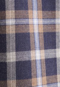 Tessuto di cotone con un motivo a quadri blu navy e marrone, con accenti azzurri e bianchi. Texture liscia con tonalità e linee a contrasto.