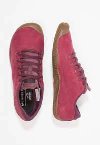 Zapatos Merrell en ante burdeos con suela de goma texturizada, que cuentan con cordones oscuros y un cuello acolchado para mayor comodidad.