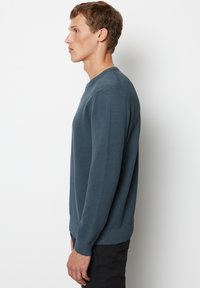Dunkelblauer Pullover aus Strickmaterial, mit Rundhalsausschnitt, langen Ärmeln und gerippten Bündchen sowie Saum. Texturiertes Muster über das gesamte Kleidungsstück.