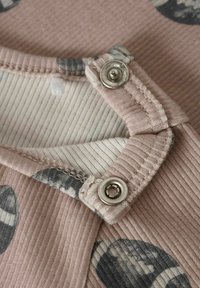 Geribbeld roze stof met grijze cirkelpatronen. Bevat een drukknoopsluiting en een binnenvoering van lichtgestreepte stof.