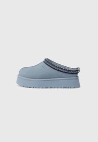 Light blue slip-on shoe with a smooth upper material, textured trim, and a thick, rounded sole. Features stitched detailing at the collar.