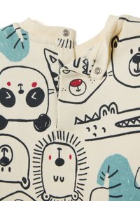 Cremfarbener Overall mit verspielten Tierillustrationen in Schwarz und Teal, mit rundem Ausschnitt und Druckknopfverschluss an der Schulter.