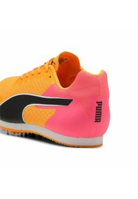 Sportskor med en livfull orange stickad överdel, svart sidopanel och ljusrosa häl med präglad logotyp. Texturen är ventilerande.