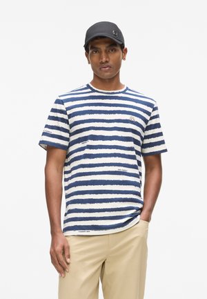Marineblauw-wit gestreept T-shirt met korte mouwen, ronde halslijn en een logo-accent op de borst, gecombineerd met beige broek.