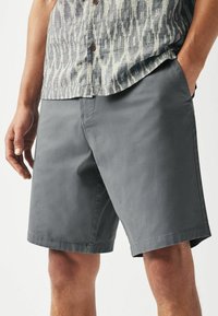 Grå shorts lavet af letvægtsstof, med flad-front design, sidelommer og lige kant. Ingen synlige mønstre eller udsmykninger.