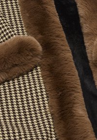 Bruin nep bont langs een houndstoothpatroon in beige en donkerbruin, met een gladde zwarte textuur ertussen.