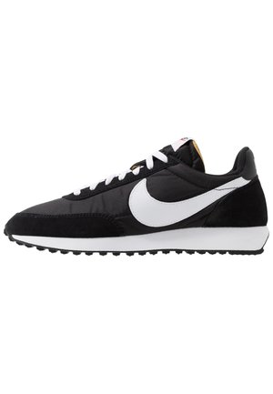 Czarno-biały but do biegania Nike z białym logo Swoosh, białymi sznurówkami i teksturowaną podeszwą zapewniającą przyczepność, widoczny z lewej strony.