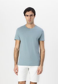 Hellblaues Baumwoll-T-Shirt mit Rundhalsausschnitt und kurzen Ärmeln, kombiniert mit weißen Shorts. Glatte Oberfläche, lässige Passform.