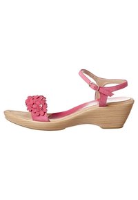 Pink suede wedge sandals featuring a floral accent on the strap, adjustable ankle buckle, and wood-textured midsole.