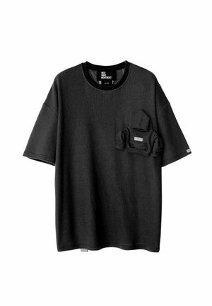 Camiseta negra de manga corta hecha de una tela texturizada, con un bolsillo en el pecho que incluye un bolsillo más pequeño en su interior. Cuello redondeado y corte relajado.
