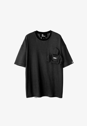 Camiseta negra de manga corta hecha de una tela texturizada, con un bolsillo en el pecho que incluye un bolsillo más pequeño en su interior. Cuello redondeado y corte relajado.