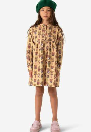 Gele jurk met een speelse dierenprint, lange mouwen en een gathered taille. Gekocht met een groene baret en roze loafers.