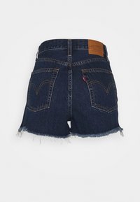 Jeansshorts i mörkblått med fransad fåll. Har bakfickor och en läderlogotyp på midjan. Klassisk femficksdesign.