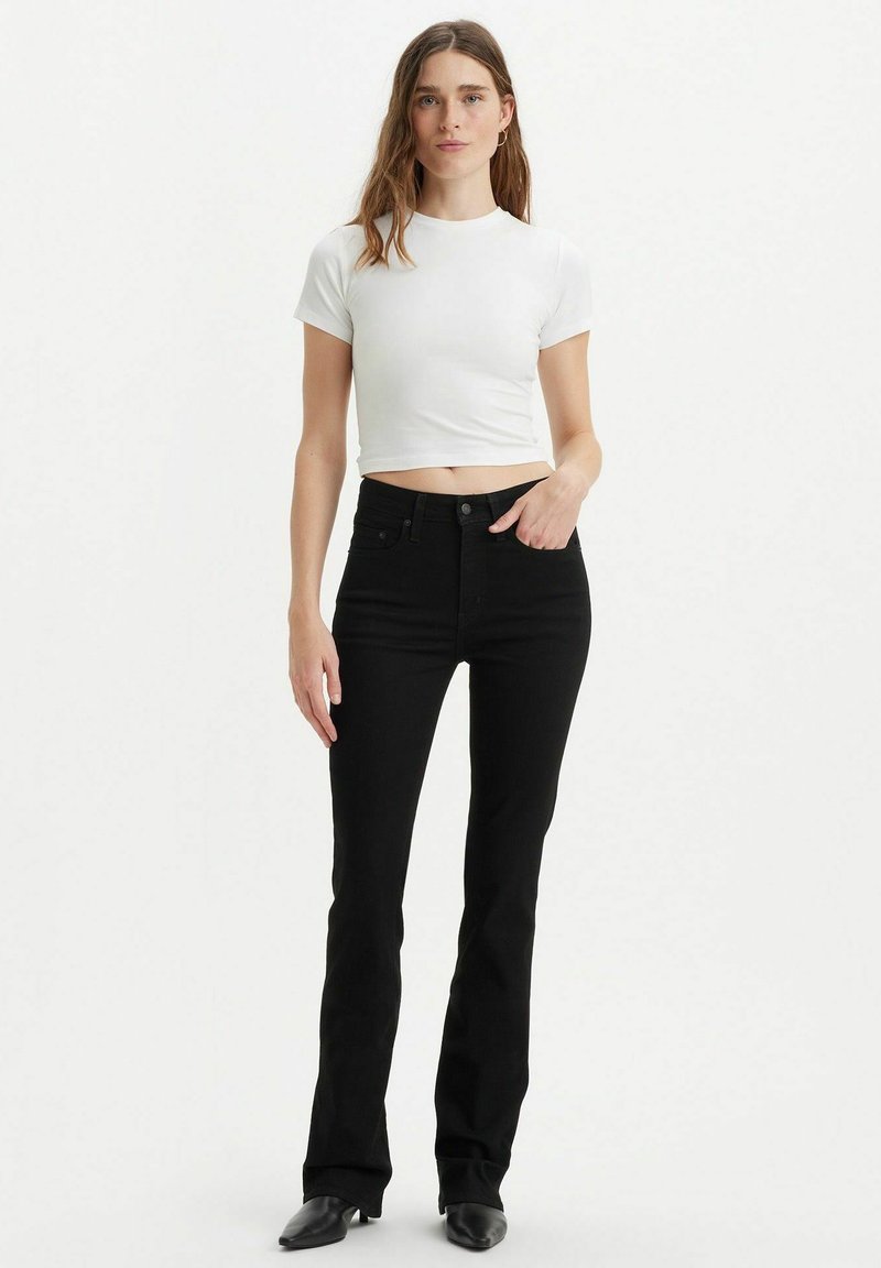 Zwarte flared jeans gecombineerd met een cropped wit T-shirt. De jeans hebben een klassiek vijf-pocket ontwerp en een hoge taille.