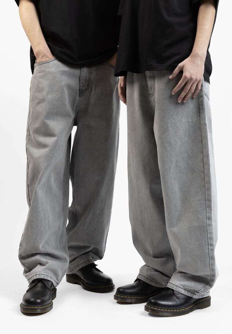 Gray denim wide-leg pants with contrasting stitching, worn with black lace-up shoes. The fabric has a soft texture.