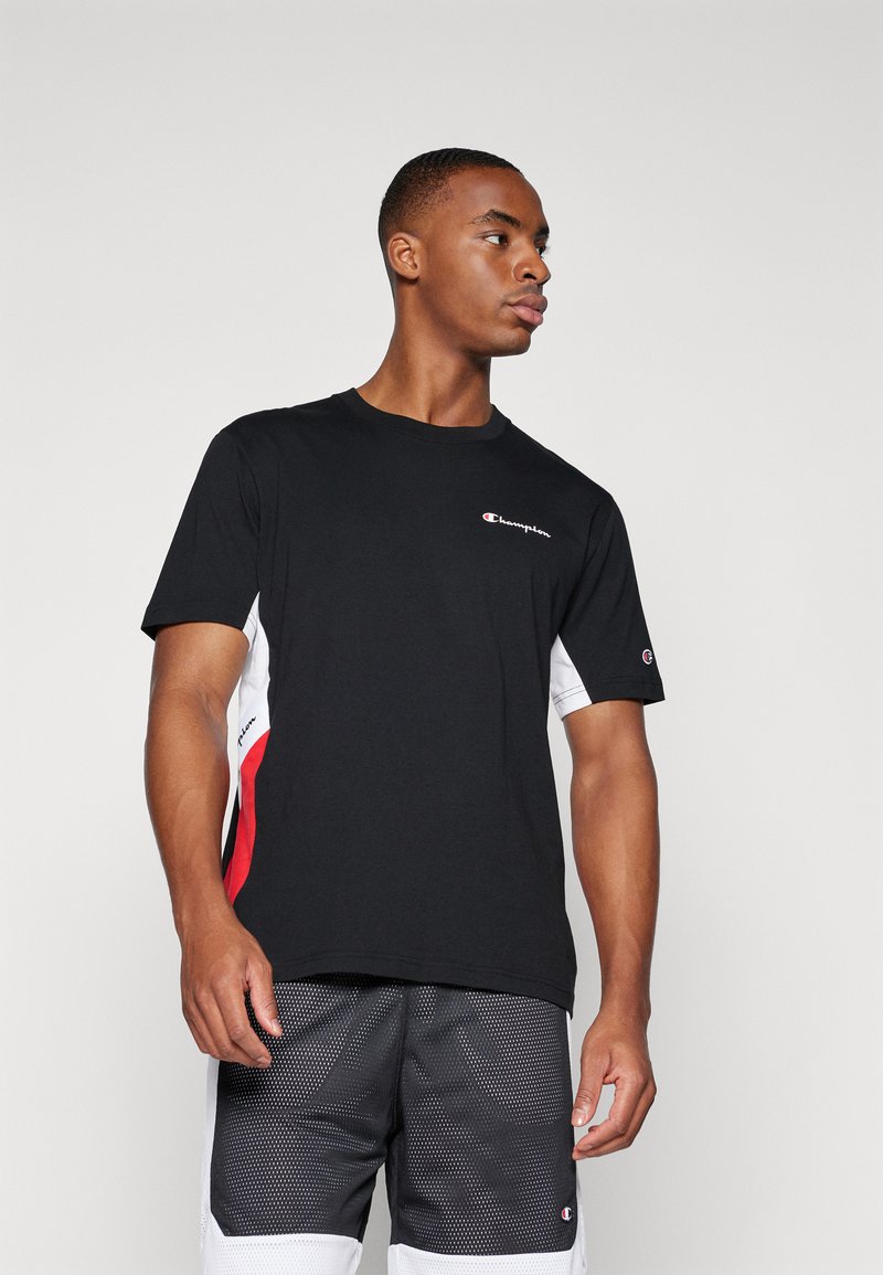 Camiseta de manga corta negra con paneles laterales en blanco y rojo, que presenta un pequeño logotipo de Champion en el pecho y un detalle bordado en la manga.