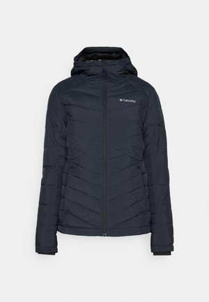 Veste matelassée rembourrée bleu marine avec capuche, dotée d'une fermeture éclair intégrale et d'un logo discret en haut à gauche.