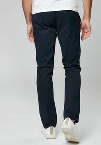 Laivastonsiniset chinot slim fit -mallilla, puuvillasekoituksesta valmistettu kangas ja sivutaskut; yhdistetty valkoisiin tennareihin, joissa on tekstuuri kantapäässä.
