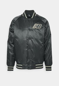 Veste bomber en satin noir avec boutons-pression à l'avant, col, poignets et ourlet côtelés avec rayures blanches, et logo New Balance beige sur la poitrine gauche.