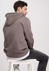 Szary sweatshirt z kapturem o miękkiej fakturze, wyświetlany z tyłu. Posiada kieszeń kangurzą oraz luźny krój.