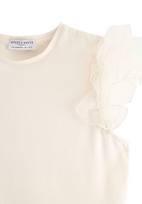 Lyse beige T-shirt med rund hals og en gennemsigtig flæsedetalje på den ene skulder. Blødt stof, minimalistisk design.
