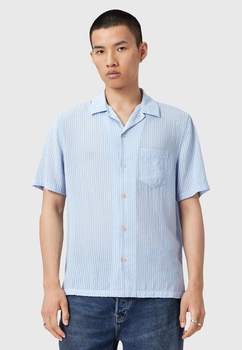 Camicia blu chiaro a maniche corte con righe verticali, chiusura a bottoni, taschino sul petto e vestibilità comoda. Realizzata in tessuto testurizzato.